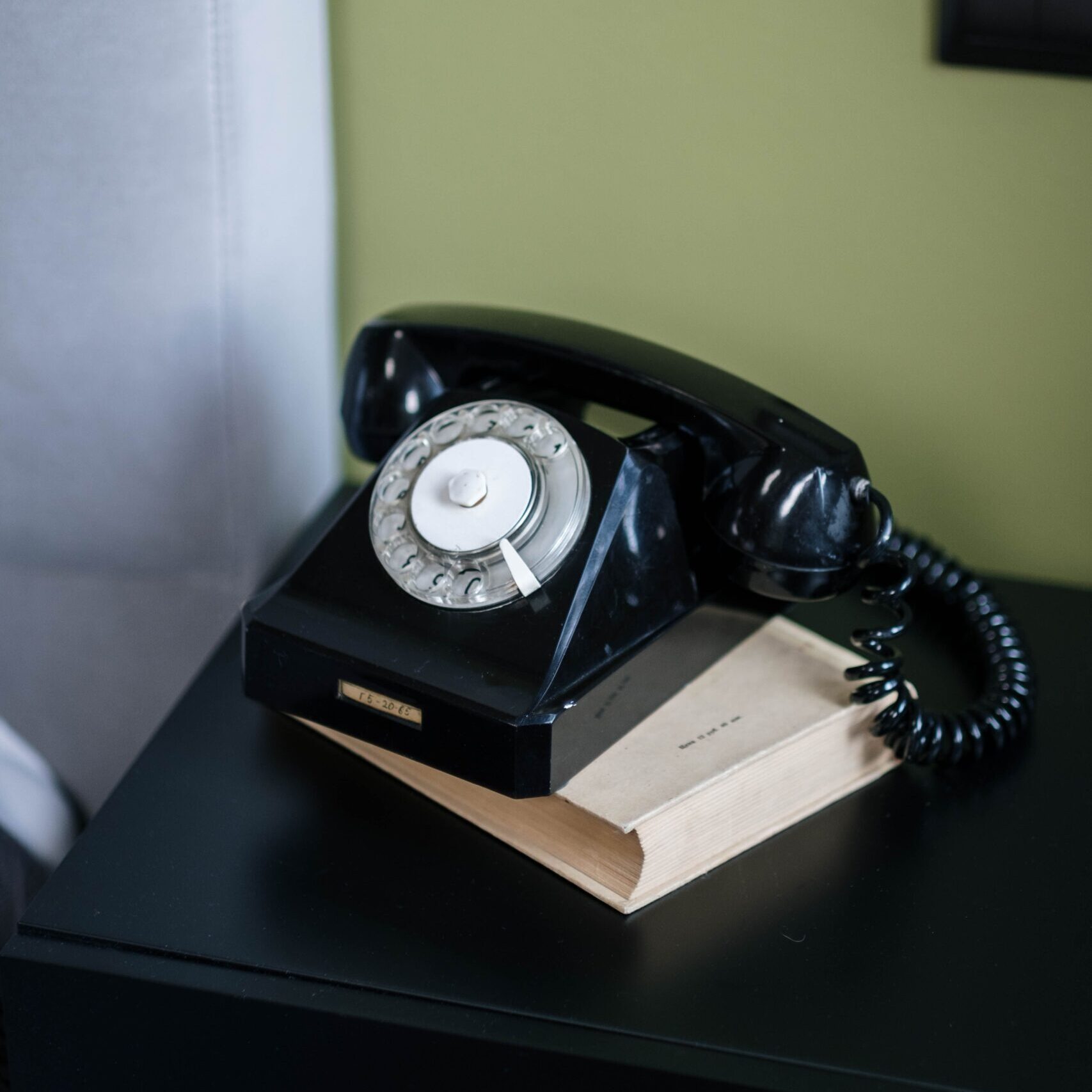 A nostalgic black rotary dial telephone on a desk, evoking retro style.
